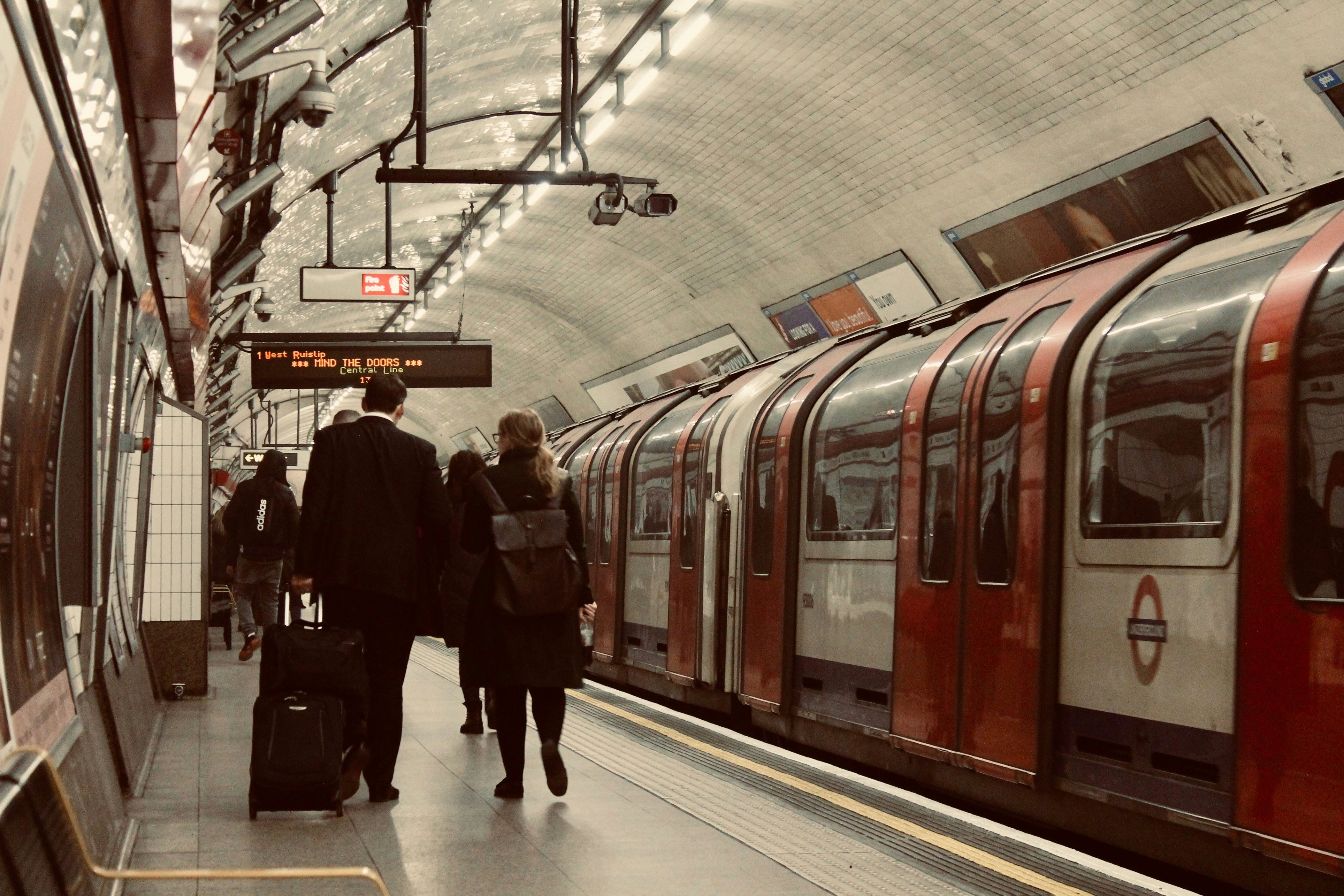 man in black coat standing beside red train